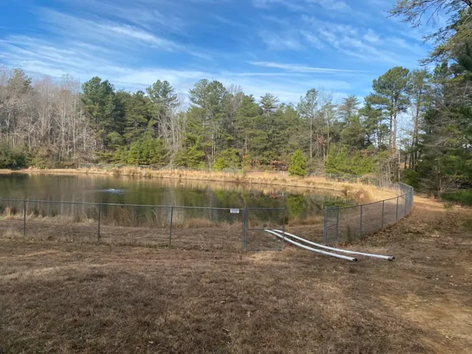 A stormwater management pond bordered by trees on a project site